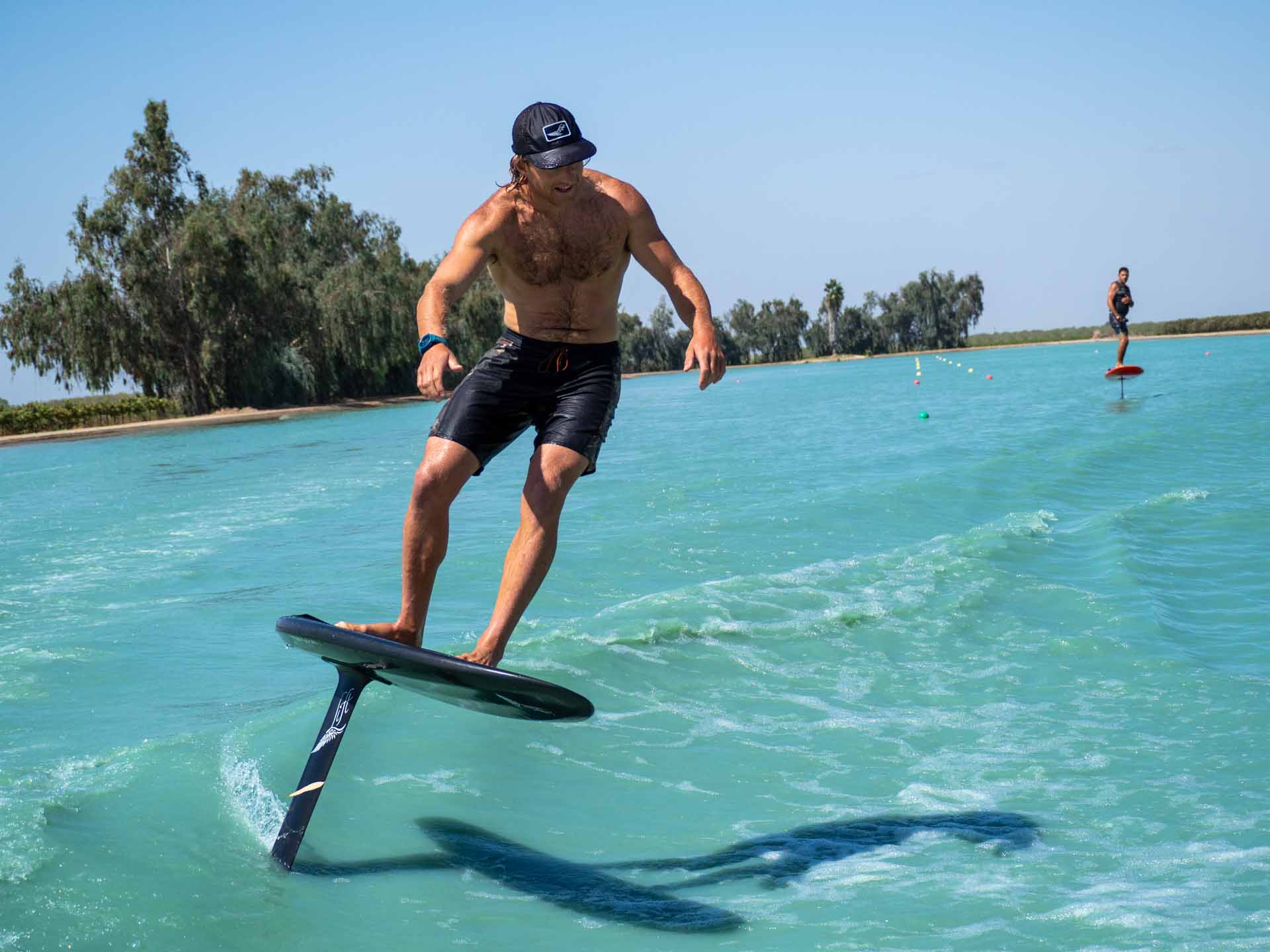 Expert surf foiler with eFoil in the background